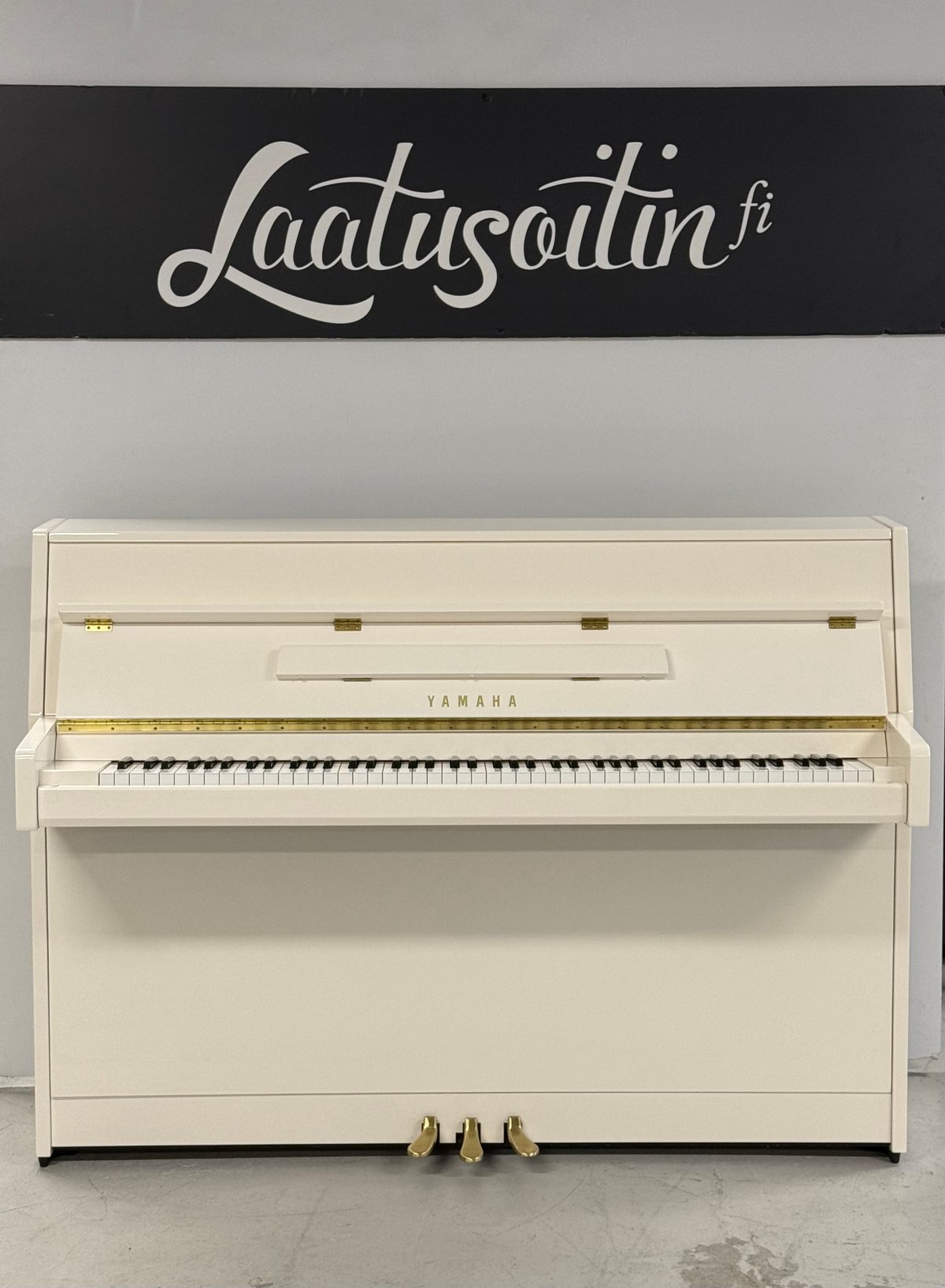 Yamaha B1, valkoinen kiiltävä pystypiano edestä, kolme messinkipedaalia