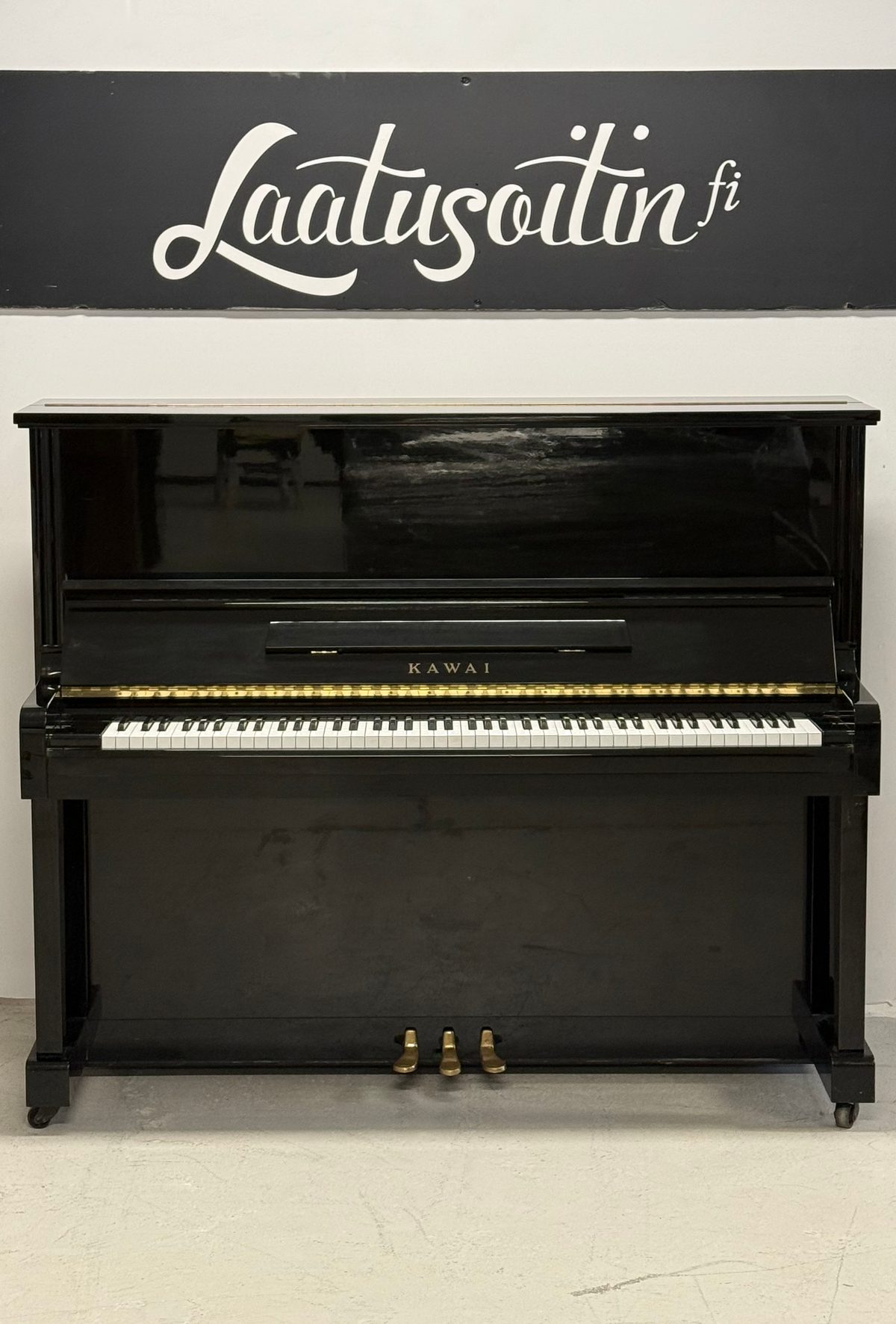 Kawai BL-31, musta kiiltävä pystypiano edestä, kolme messinkipedaalia
